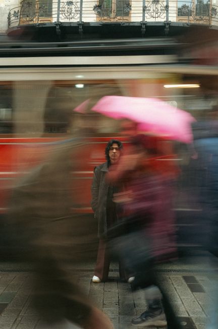 A person standing still as the city life blurs around, featuring vibrant city motion.
