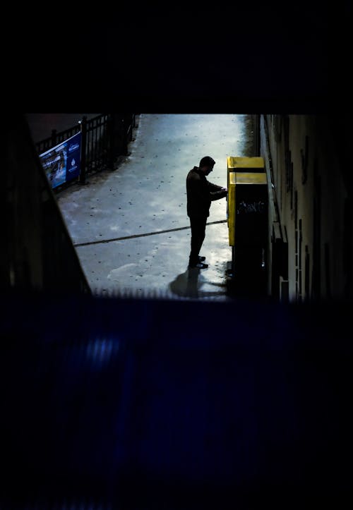 A man is standing in the dark at a subway station