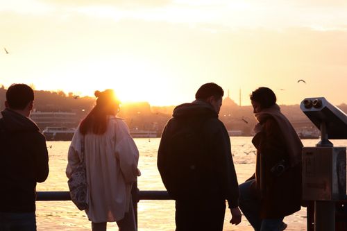 Free Friends standing at the Bosphorus strait during sunset, Istanbul skyline in the background. Stock Photo
