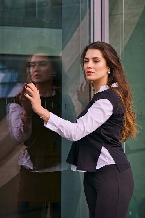 Elegant Woman Posing next to a Glass Wall of a Modern Building 