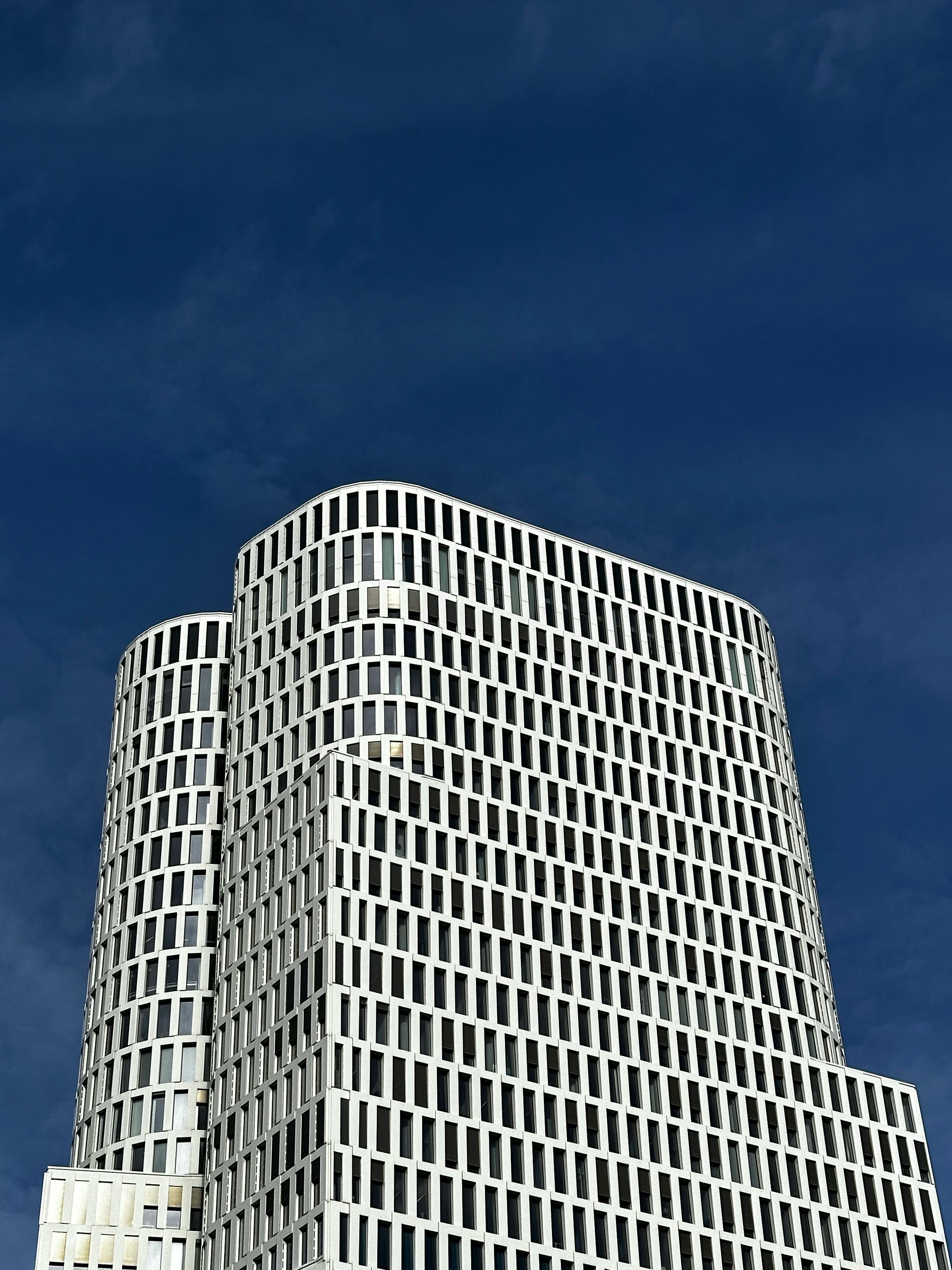 A contemporary skyscraper with a striking facade against a clear blue sky.