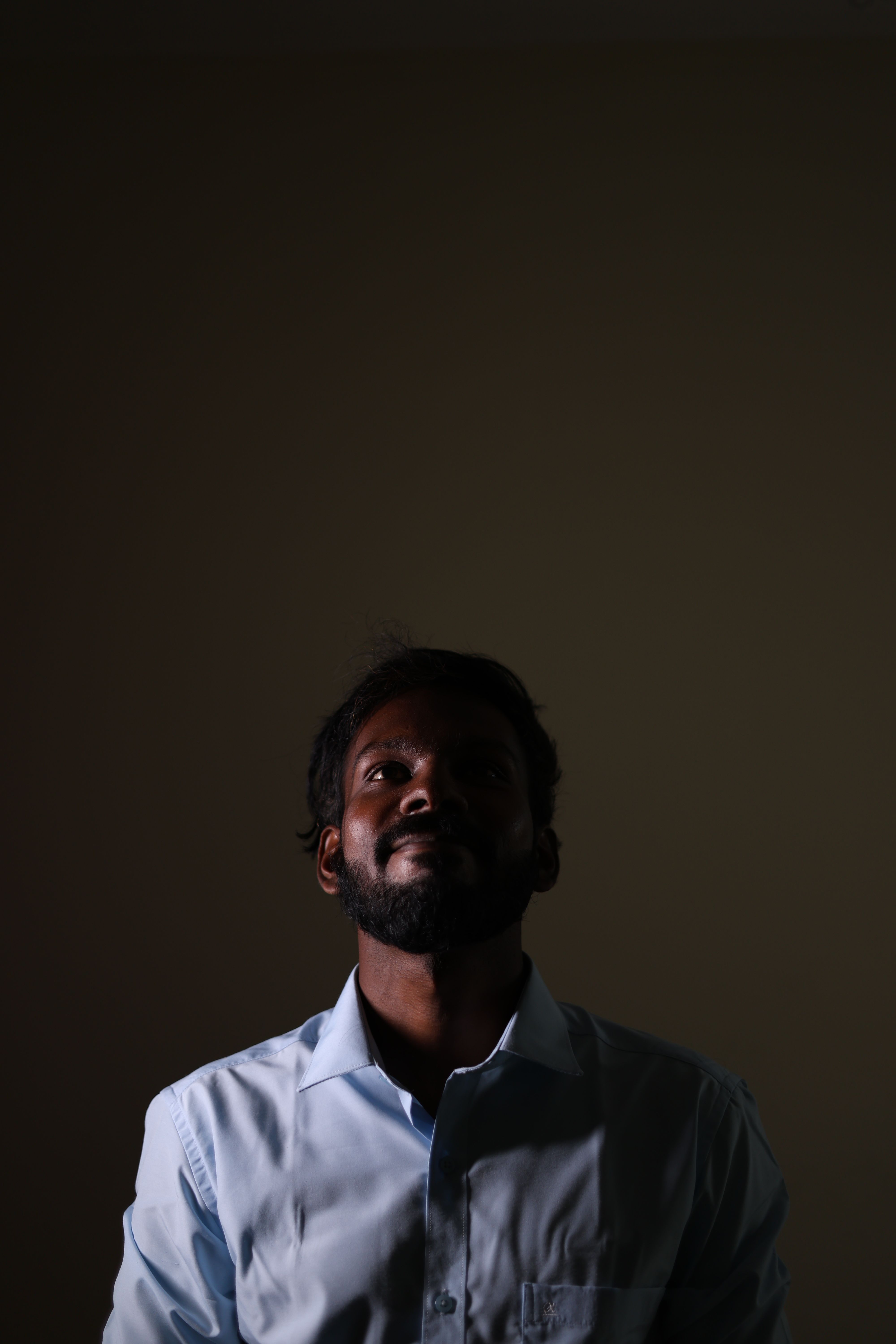 Dramatic portrait of a man looking up in a dimly lit studio capturing introspection.