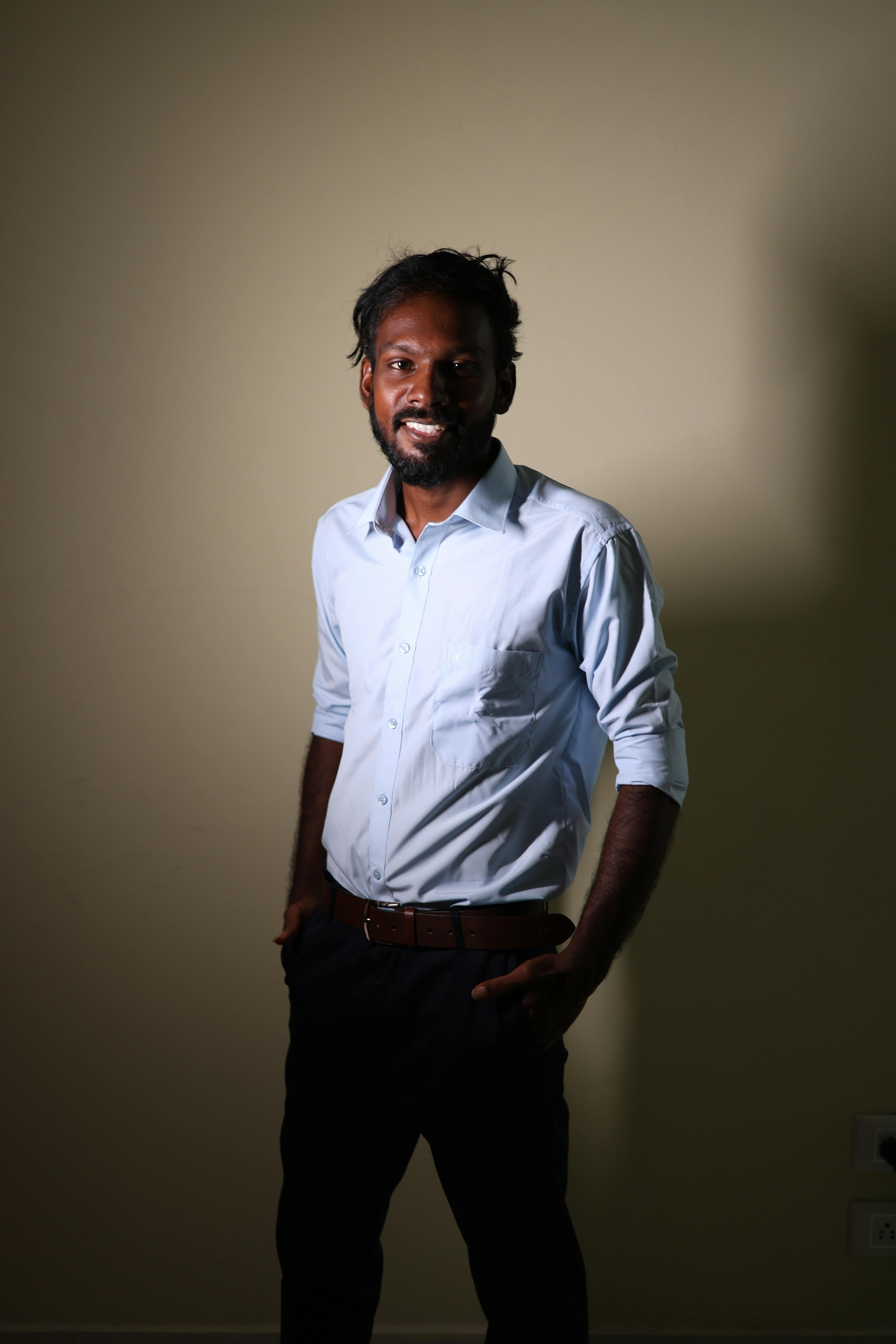 Portrait of a smiling man in a white shirt, posing indoors with warm lighting.