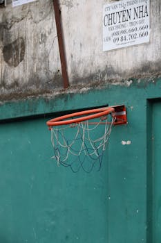 Close-up of a basketball hoop on a weathered wall in an urban setting, evoking a sense of street sports.