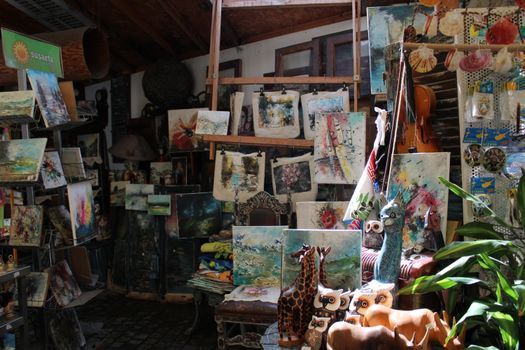Explore a vibrant indoor art stall in Larnaca, Cyprus, showcasing colorful handmade paintings and crafts.