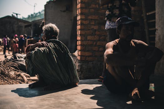 一群成年人坐在村庄的户外，在阳光明媚的日子里投下浓重的影子
