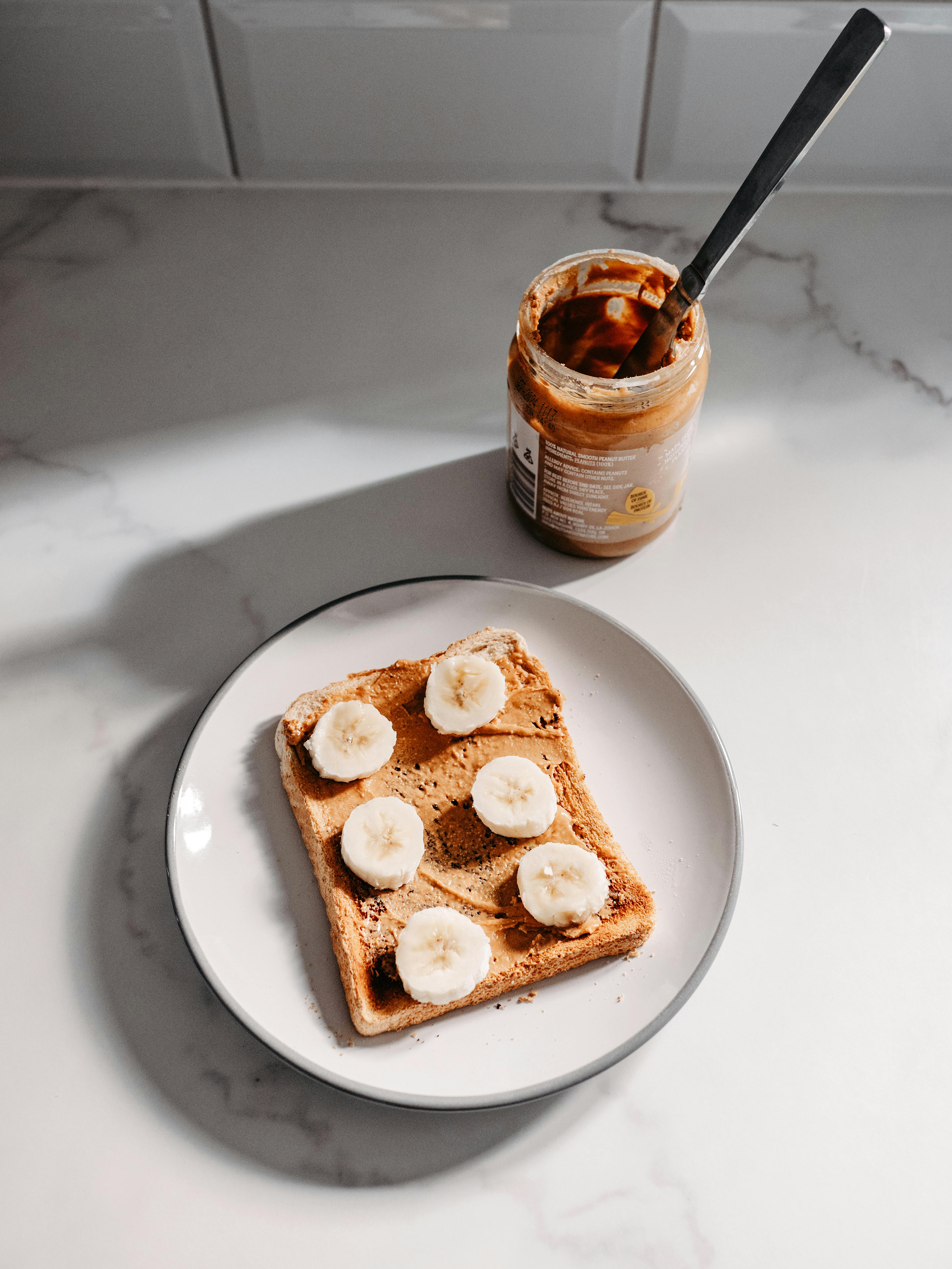 A delicious slice of toast with peanut butter and banana slices on a white plate, perfect for breakfast or snack.
