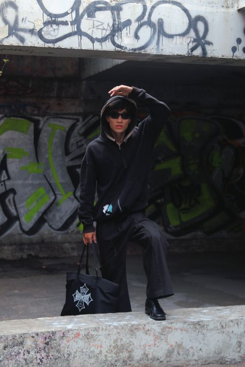 Free Stylish model poses in urban setting with graffiti backdrop, wearing black attire and sunglasses. Stock Photo
