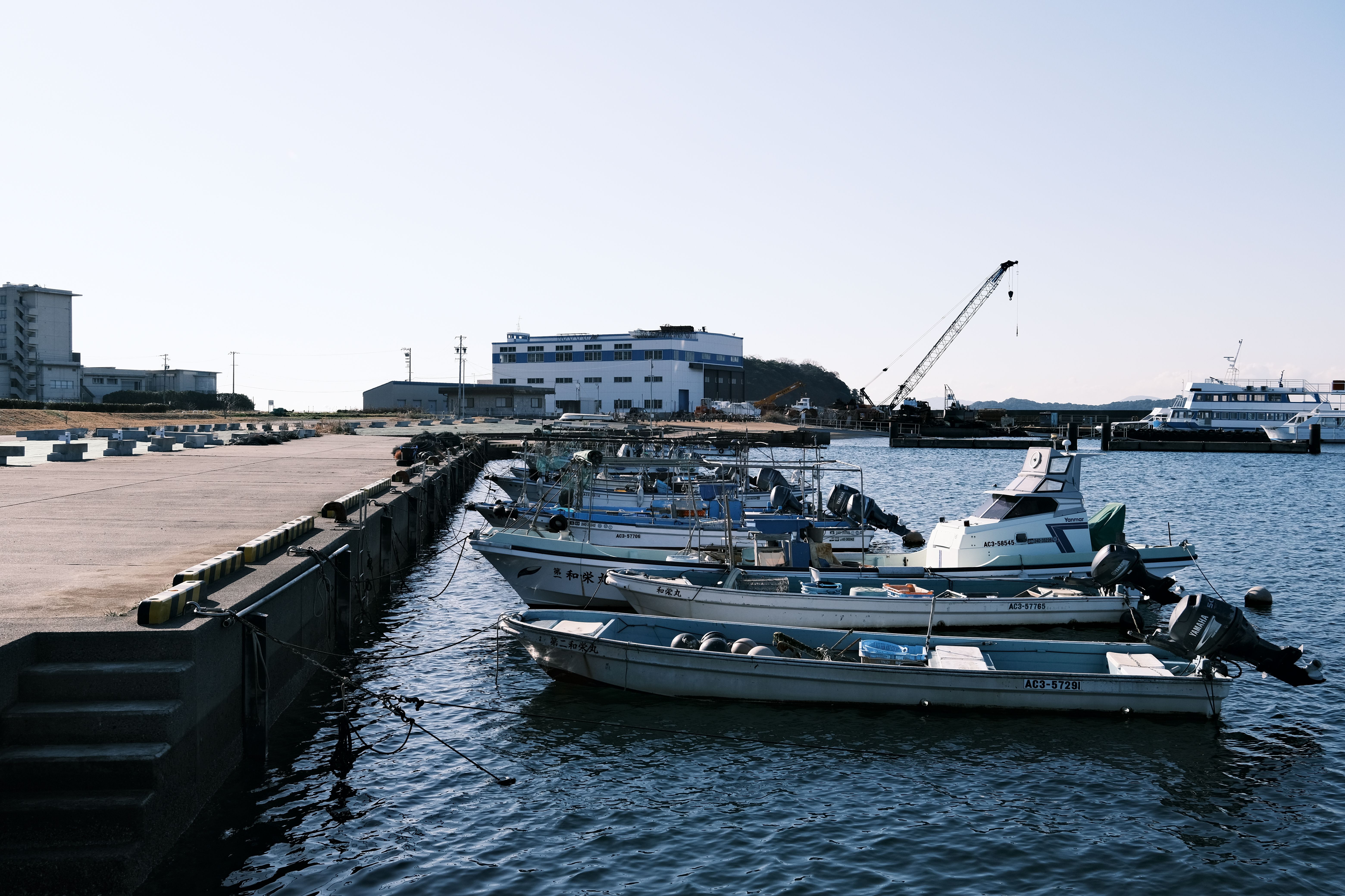 A peaceful scenery of moored boats at Gamagōri harbor in Japan, under a clear blue sky.