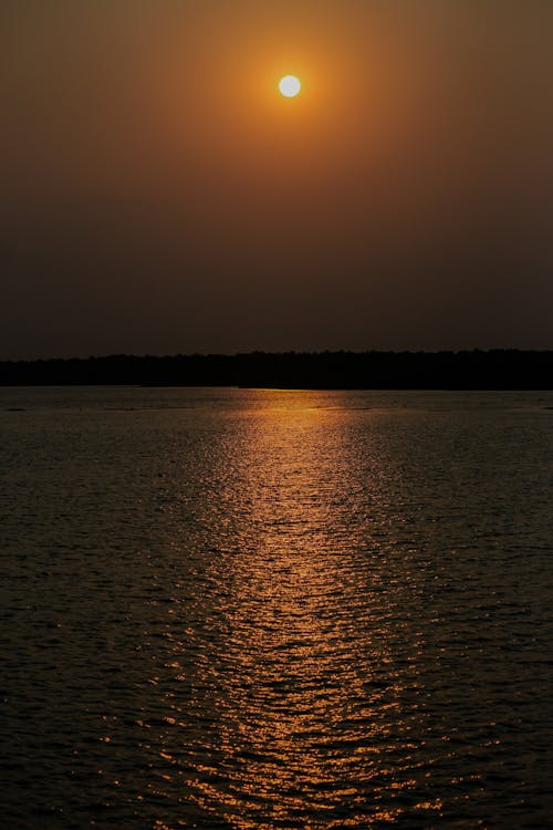 A sunset over a body of water with a boat