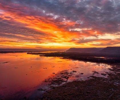 Vibrant sunset reflecting over the water near Weaver, Minnesota, creating a dramatic landscape.