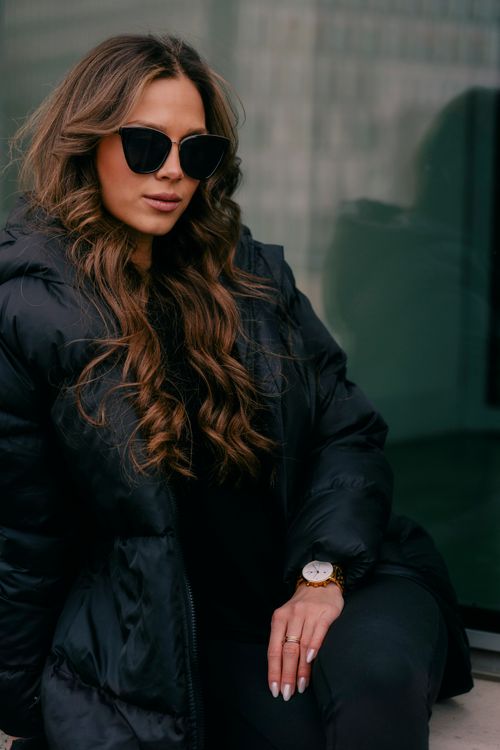 Free Stylish woman with long wavy hair in a black jacket and sunglasses in Berlin. Stock Photo