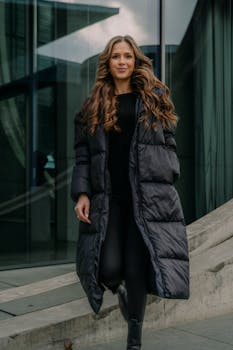Stylish woman in black coat posing in Berlin's modern architecture.