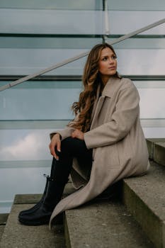Stylish woman with long hair sitting on urban stairs in Berlin, Germany.