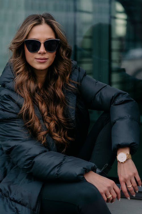 Woman with Long Wavy Brown Hair Posing in a Black Jacket and Sunglasses