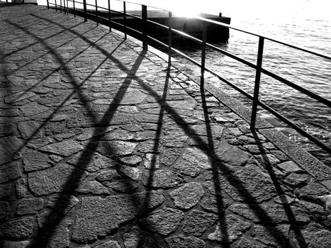 Grayscale Photography of Railings Near Body of Water