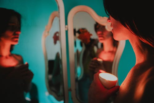 A woman holding a candle in front of a mirror