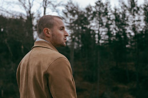 Man in a Brown Jacket Standing in a Forest 