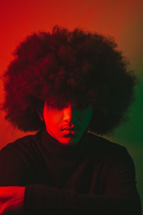 Free Model with afro hair in a studio setting with dramatic red and green lighting. Stock Photo