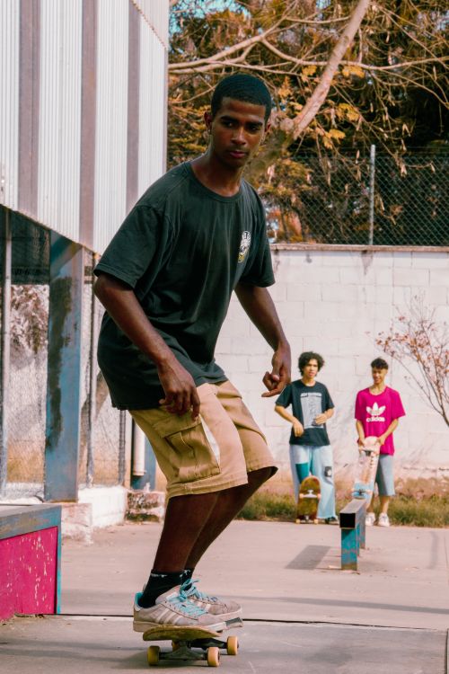 Free A young man skillfully skateboarding in an outdoor urban skate park with friends watching. Stock Photo