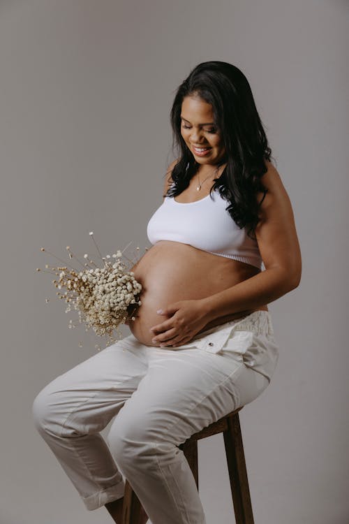 Pregnant Woman Posing in a Studio with a Dog 