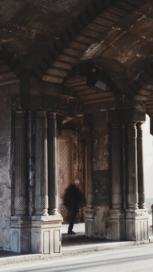 A man walking through an archway in a city