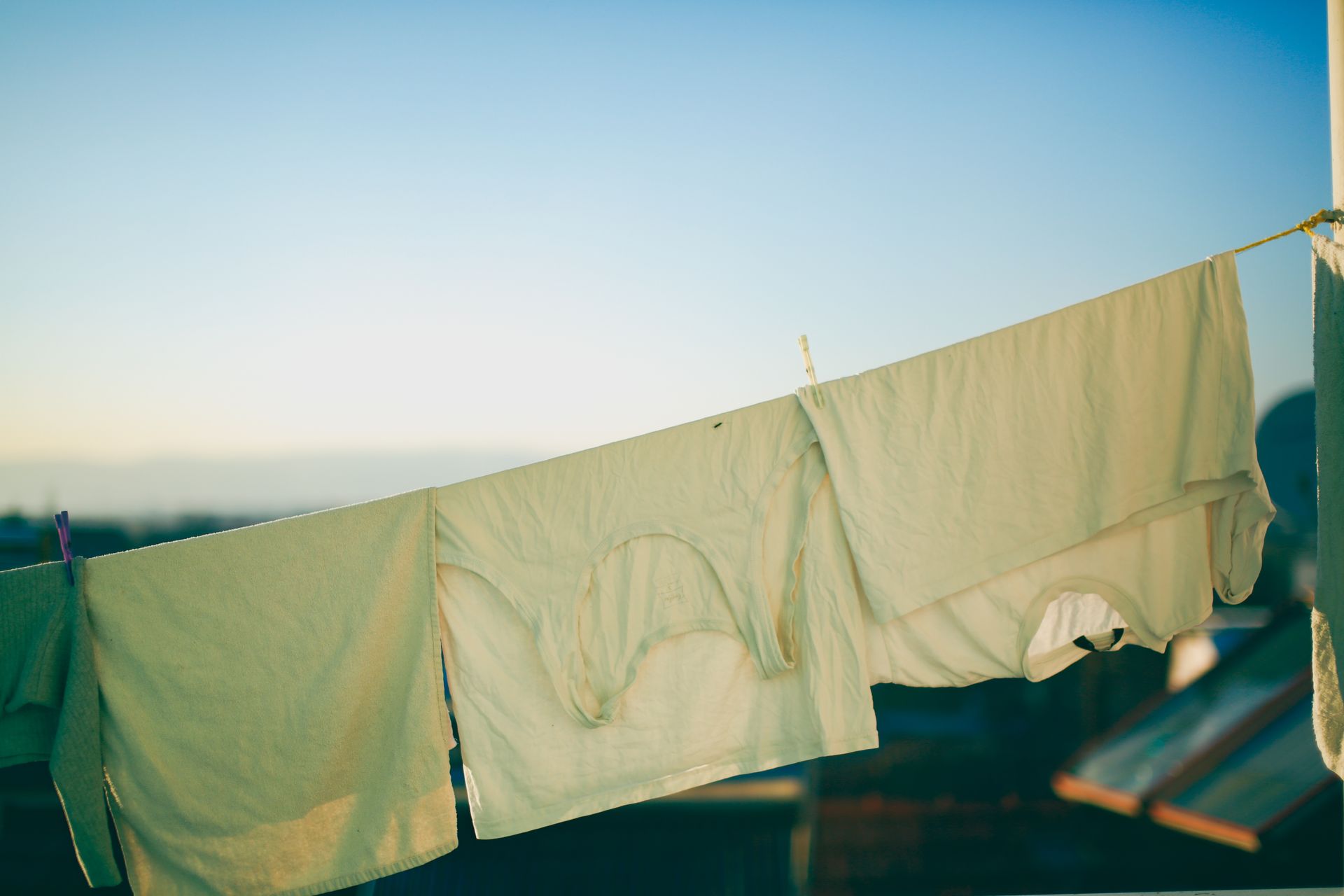 Outdoor shot of clothes drying on a string against a clear blue sky. Perfect for lifestyle and home care themes.