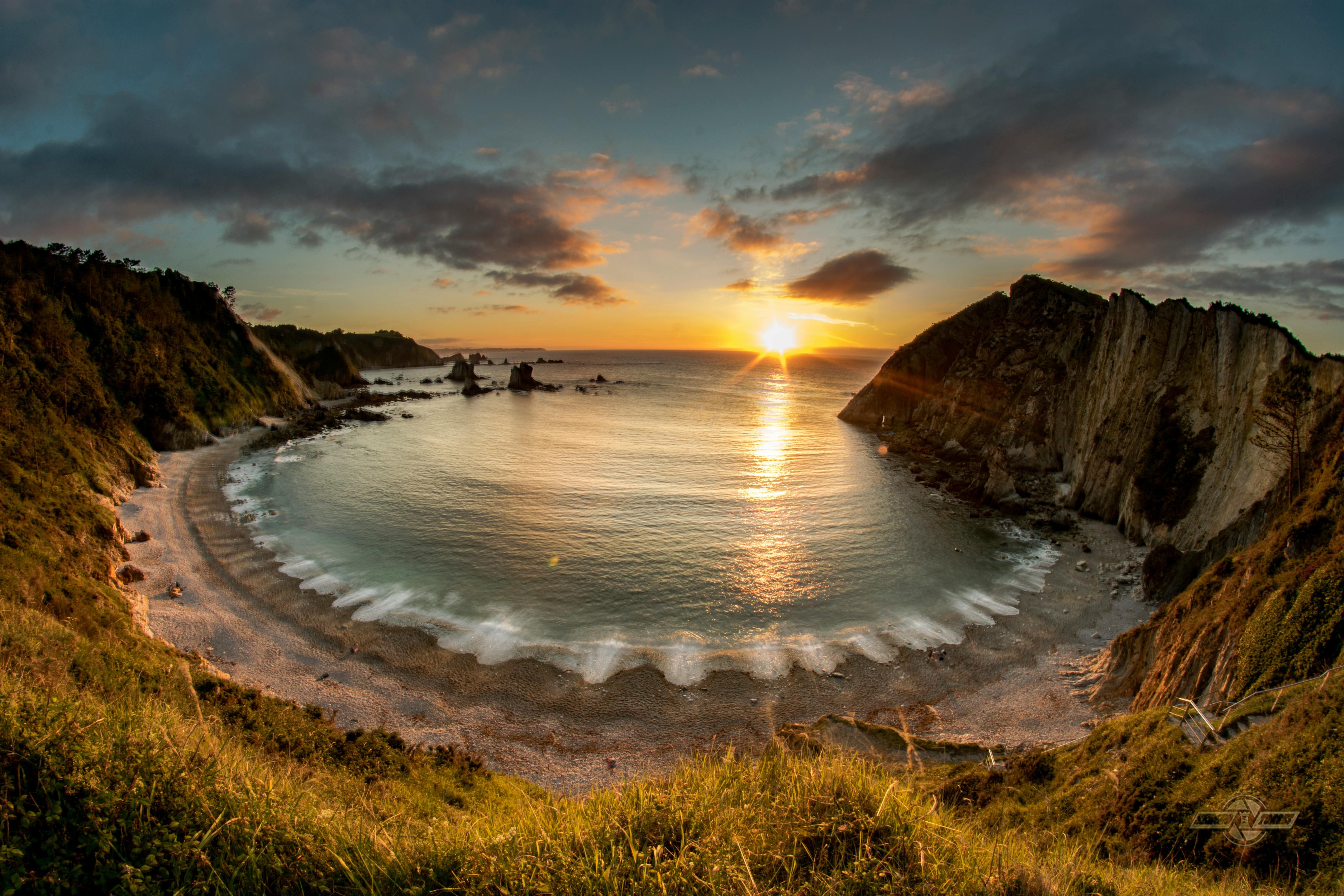 Breathtaking view of a sunset over the cliffs and bay in Asturias, Spain.