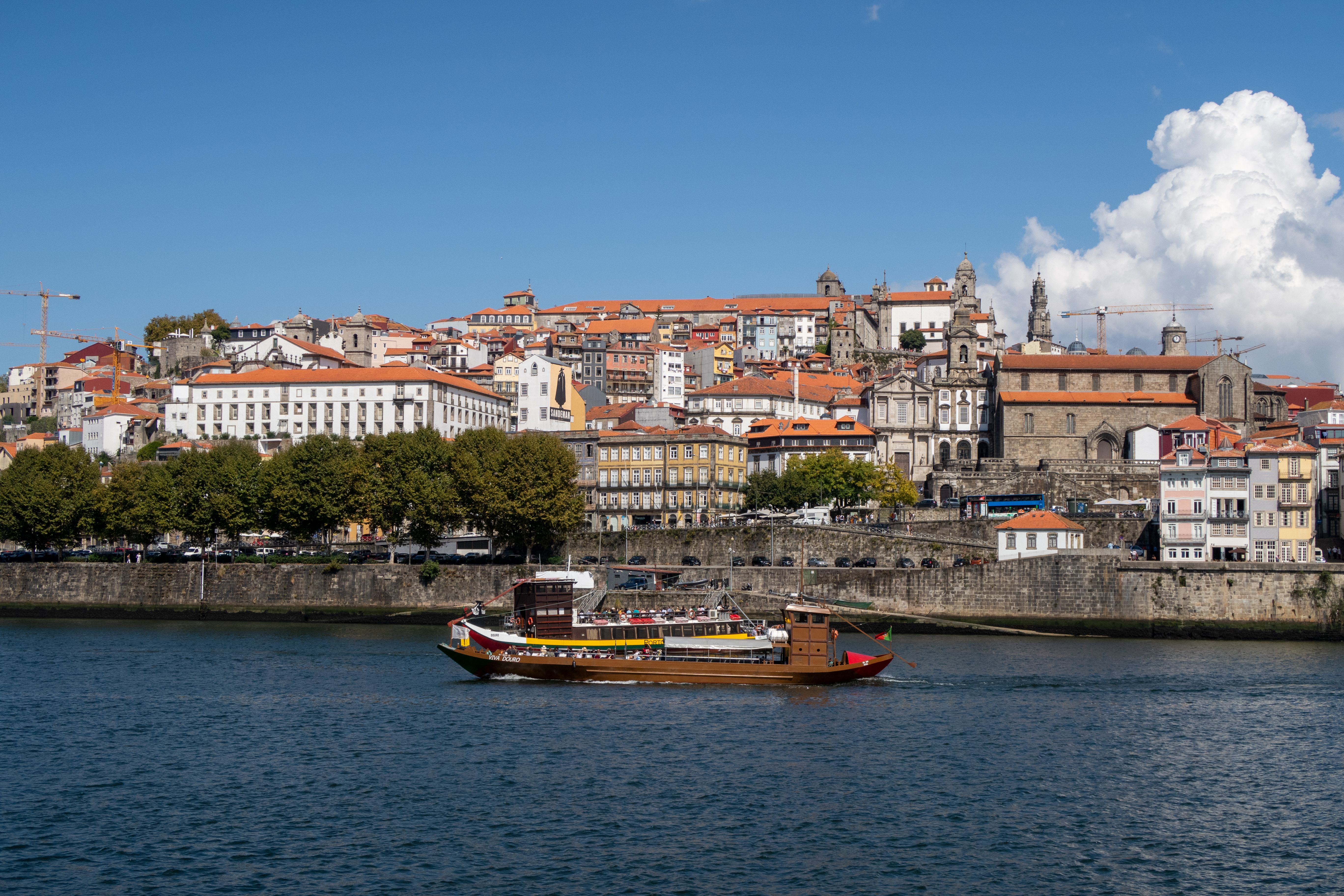 Charming Oporto cityscape with traditional boat on the Douro River under a clear blue sky. - Oporto