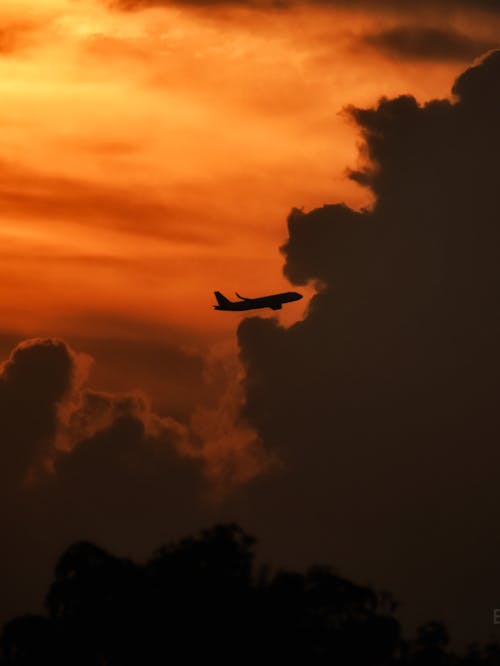 A plane flying through the clouds at sunset