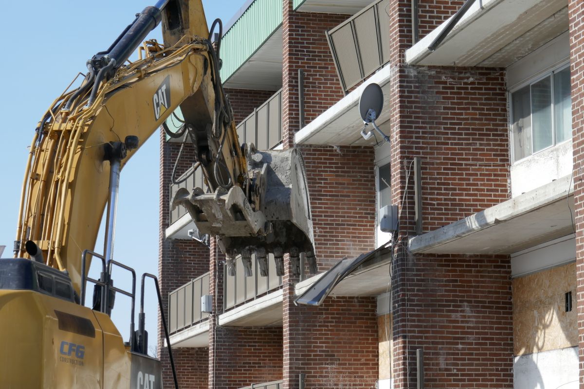 Excavatrice démolissant une maison en briques lors d'un chantier de démolition