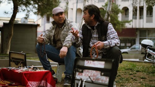 Two men sitting on a bench talking to each other
