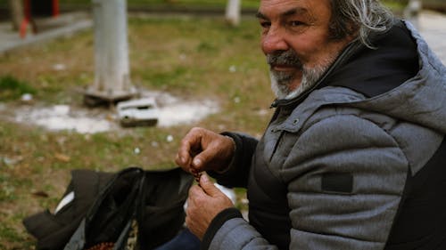 A man sitting on the ground with his hands in his pockets