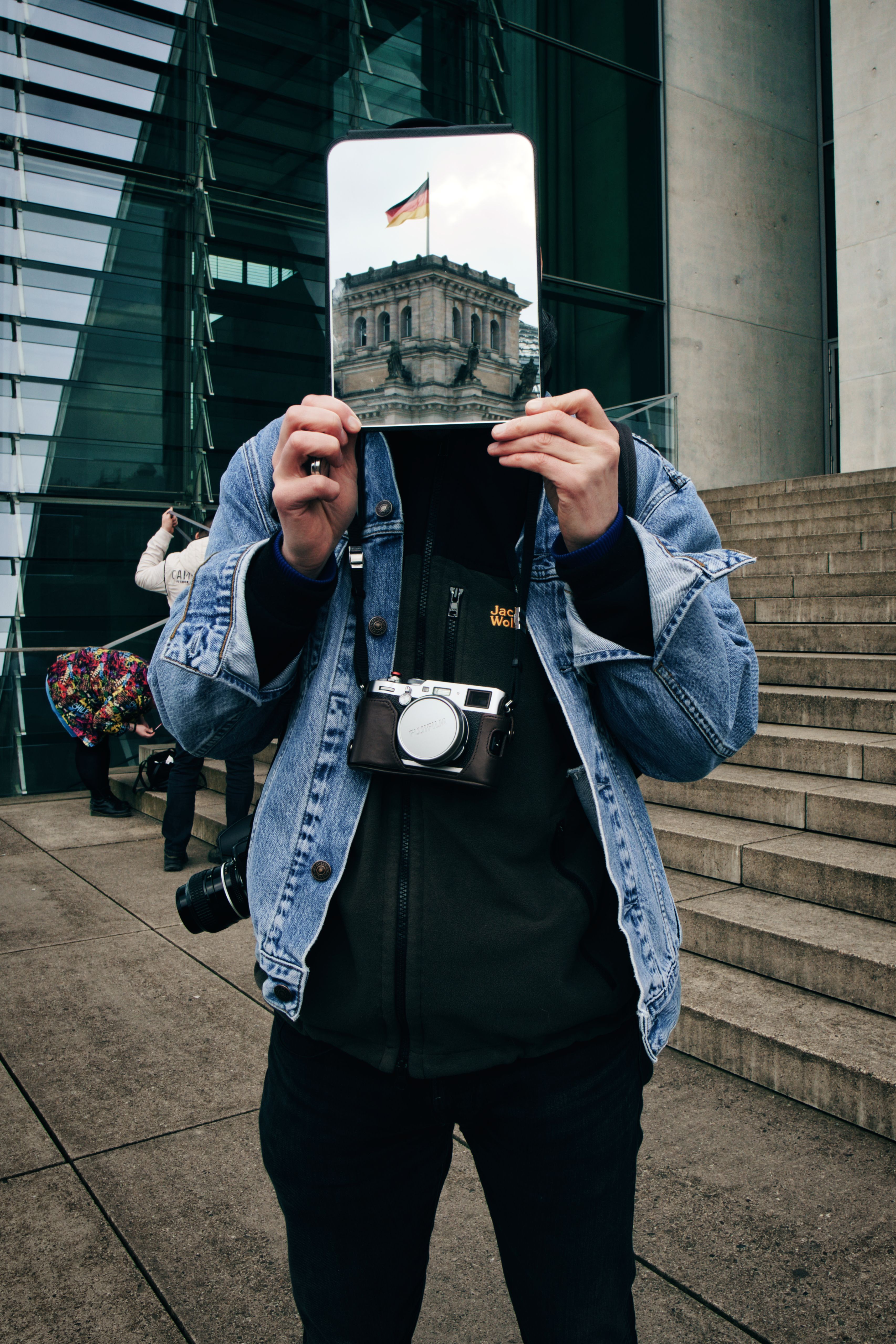 Artistic shot of a person holding a mirror reflecting Reichstag in Berlin.