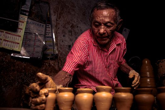 Elderly potter skillfully crafting clay pots in Tracunhaém, Brazil.
