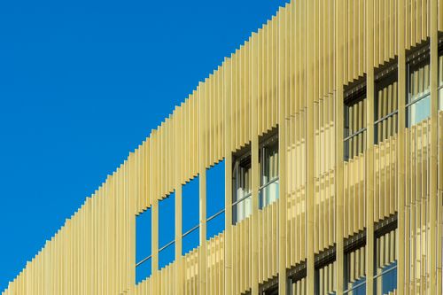 Free Contemporary building with golden facade against a clear blue sky in Alphen aan den Rijn, Netherlands. Stock Photo