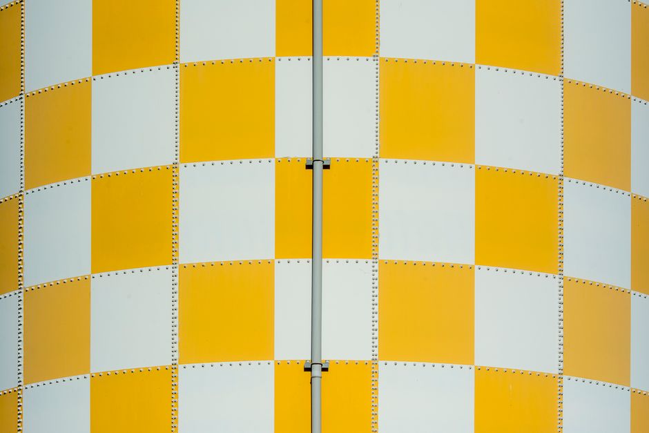Close-up of a yellow and white checkered metal wall with visible texture and rivets.