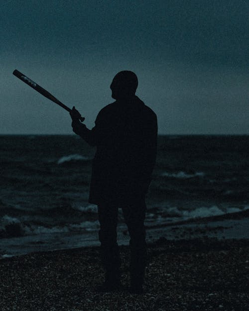A man holding a baseball bat in front of the ocean