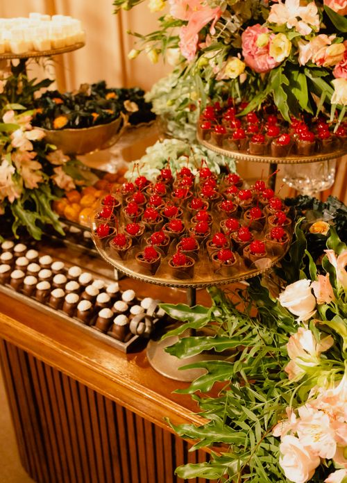 Free Elegant dessert table with floral decor and chocolate pralines for a luxurious event. Stock Photo