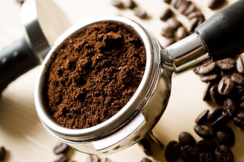 Free Close-up of freshly ground coffee in a portafilter with scattered coffee beans. Stock Photo