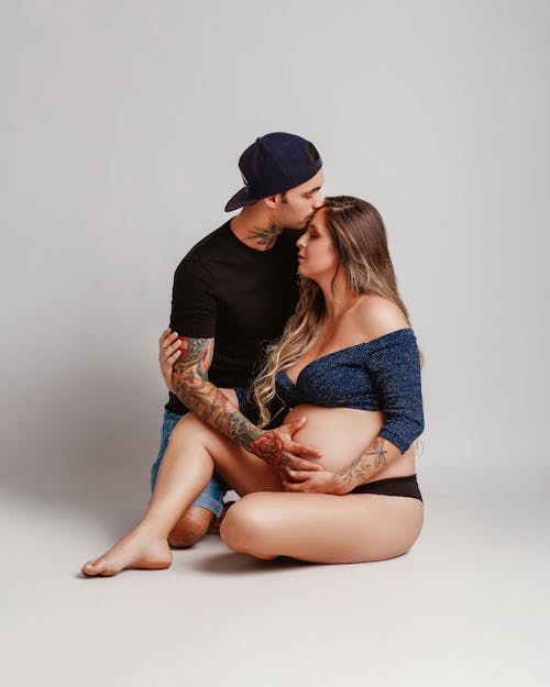A pregnant woman and man sitting on the ground