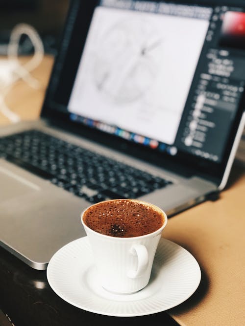 Selective Focus Photo of Coffee Cup Near Laptop