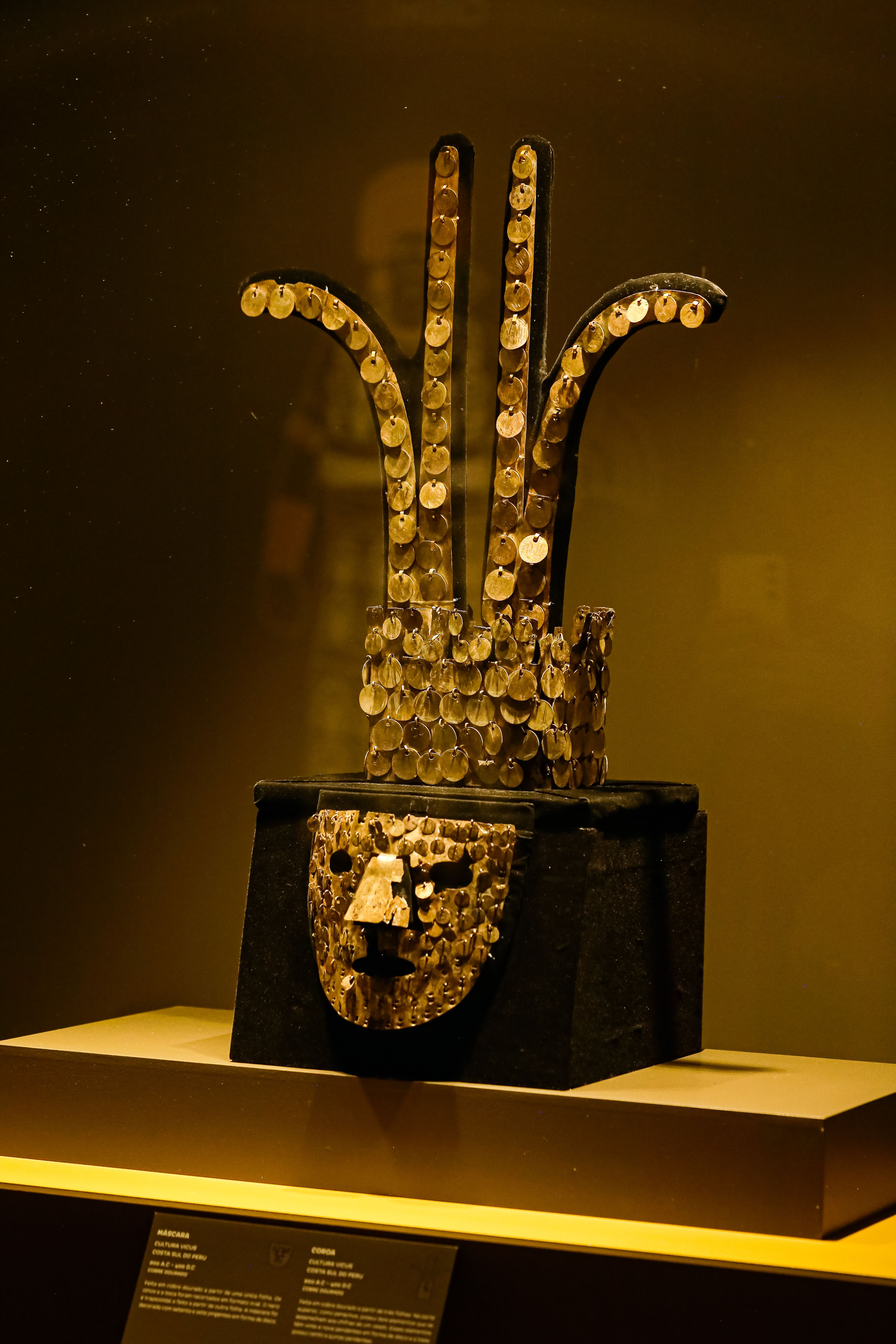 A gold mask with coins on display · Free Stock Photo