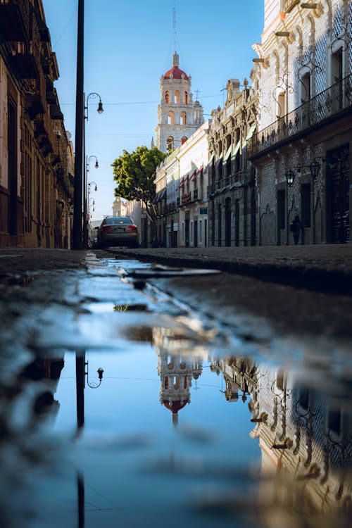 A reflection of a building in a puddle on a street