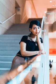 一位时尚女士在室内楼梯上摆出优雅的姿势，尽显现代气息