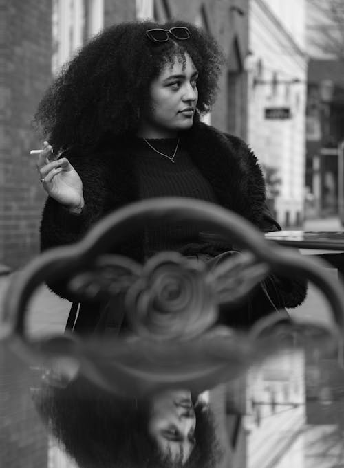 A woman with curly hair smoking a cigarette