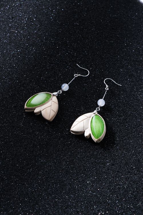 Free Close-up of stylish leaf-inspired silver earrings on a sparkling dark surface, perfect for fashion and accessory themes. Stock Photo