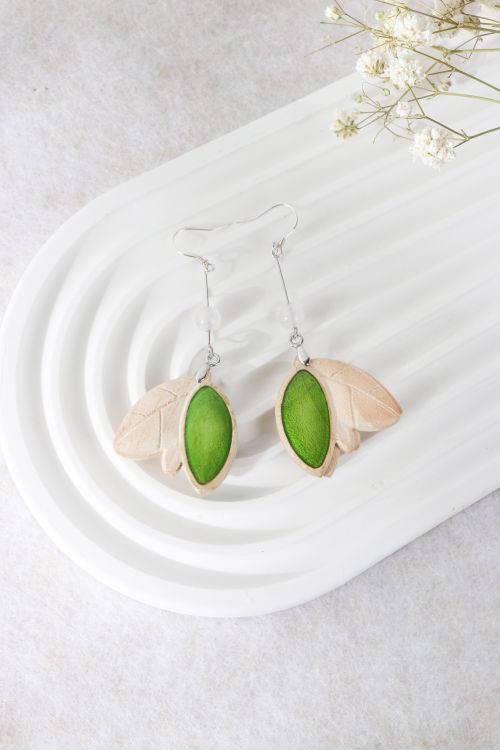 Free Leaf-shaped earrings with green stones displayed on a white textured tray. Stock Photo