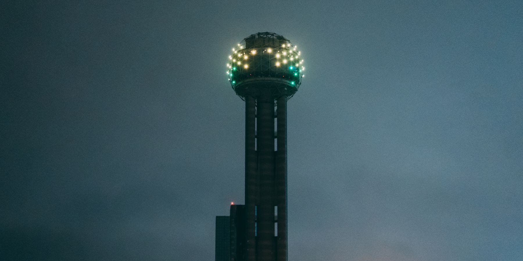 The iconic Reunion Tower glowing vividly during the night in Dallas, Texas.