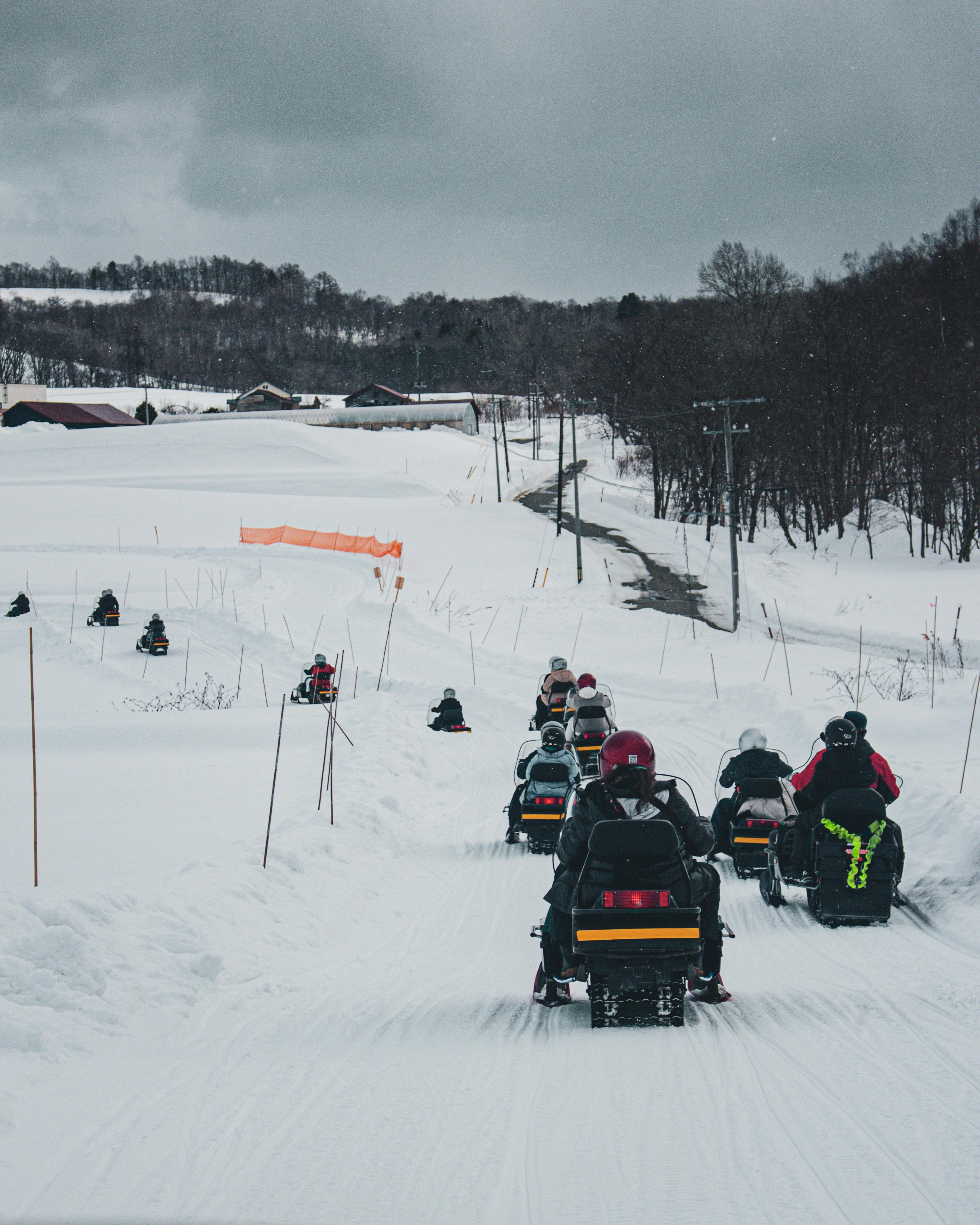 Group of people riding snowmobiles on a snowy trail, perfect for winter tourism and adventure.